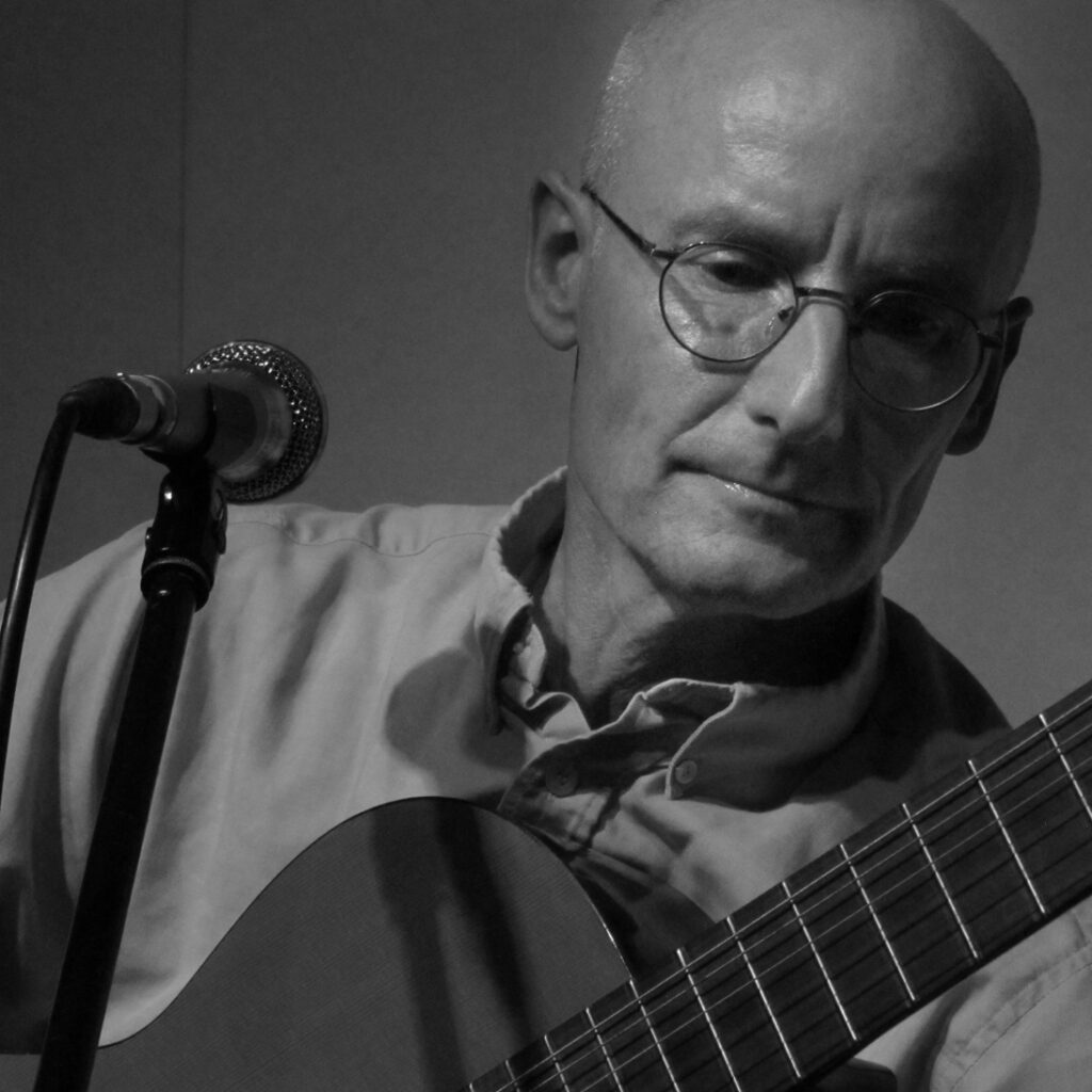 Portrait Ekkehard Maaß mit Gitarre am Mikrofon
